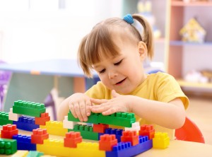 Little girl play with building bricks in preschool